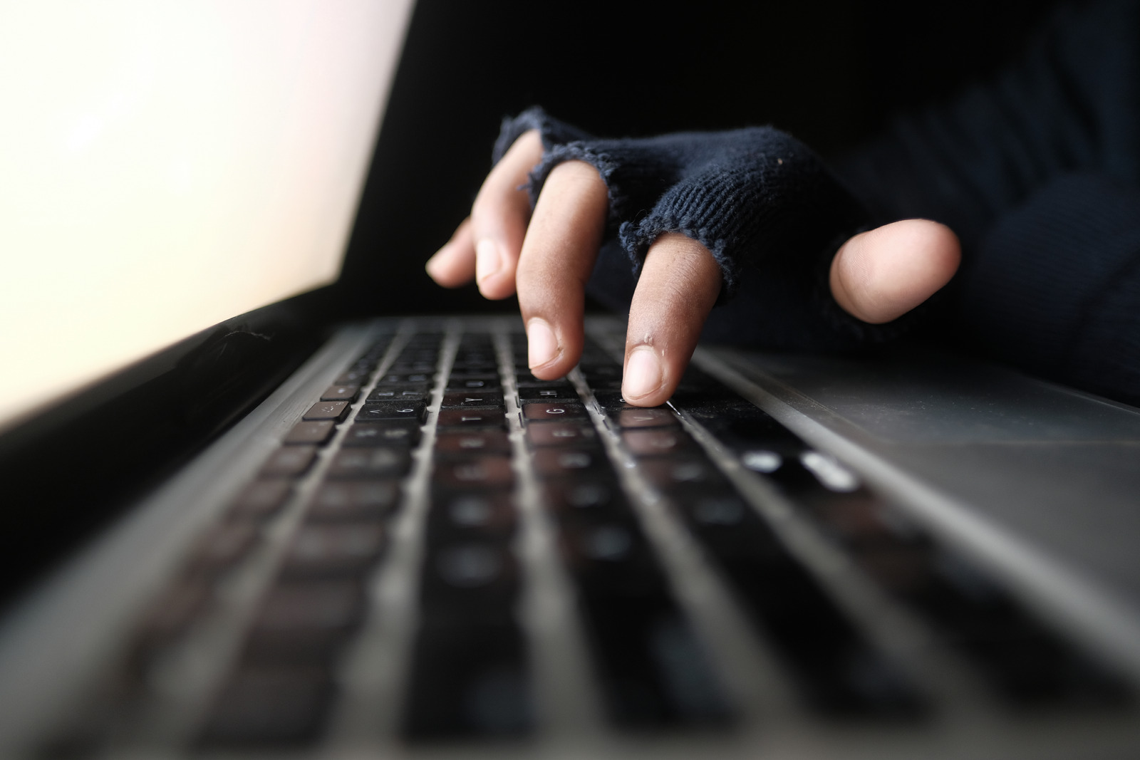 hacker hand stealing data from laptop top down.